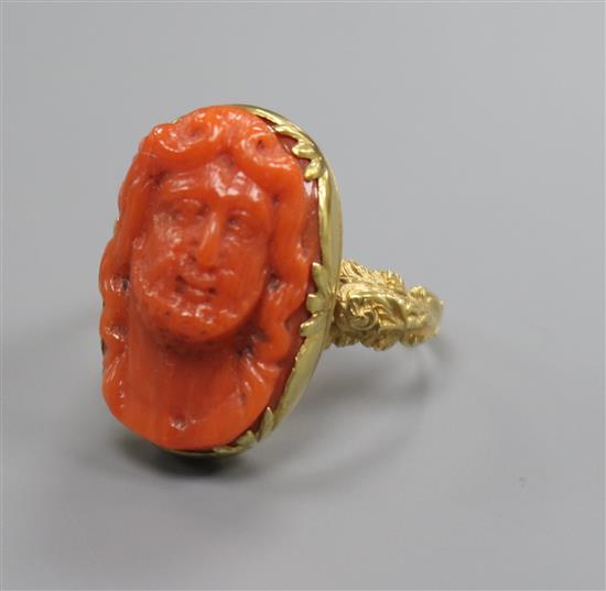 An antique yellow metal and oval coral ring, carved with the bust of a gentleman, size O.